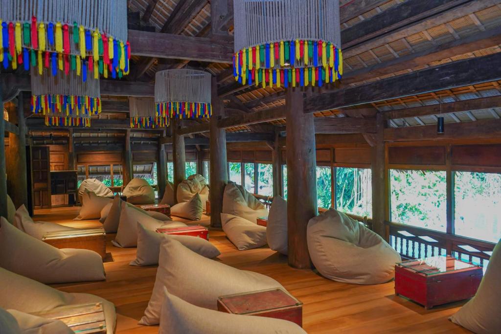 An open lounge is filled with beanbag seating beneath colourful pendant lights and timber beams.