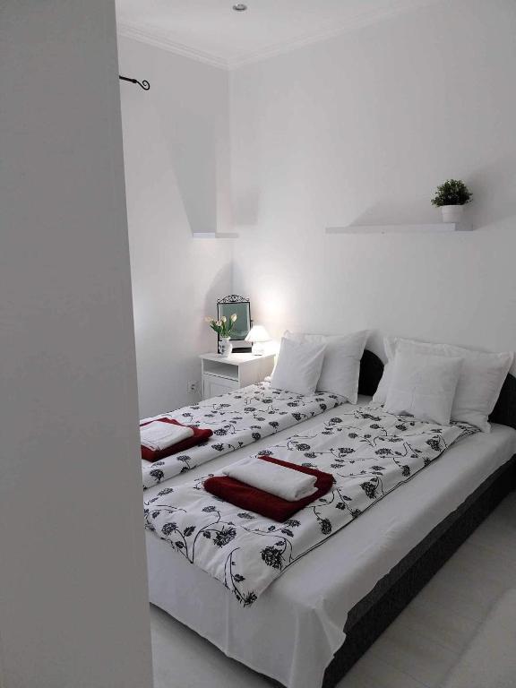 a white bedroom with a bed with red towels on it at Lake House Comfort in Zamárdi