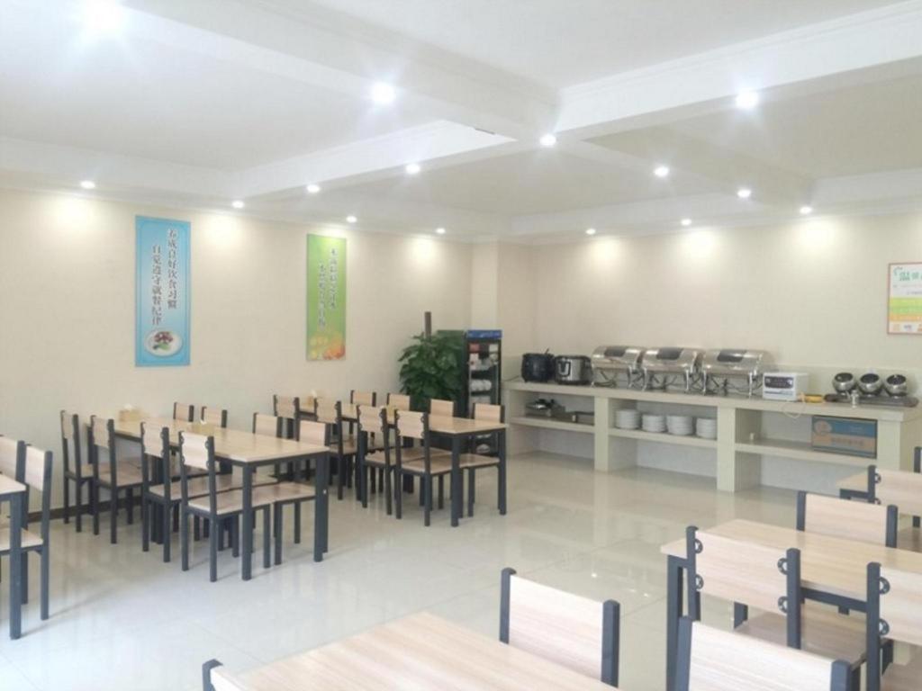 ein Esszimmer mit Tischen und Stühlen und eine Küche in der Unterkunft GreenTree Inn Beijing Daxing District Yufa Town New Airport Express Hotel in Peking