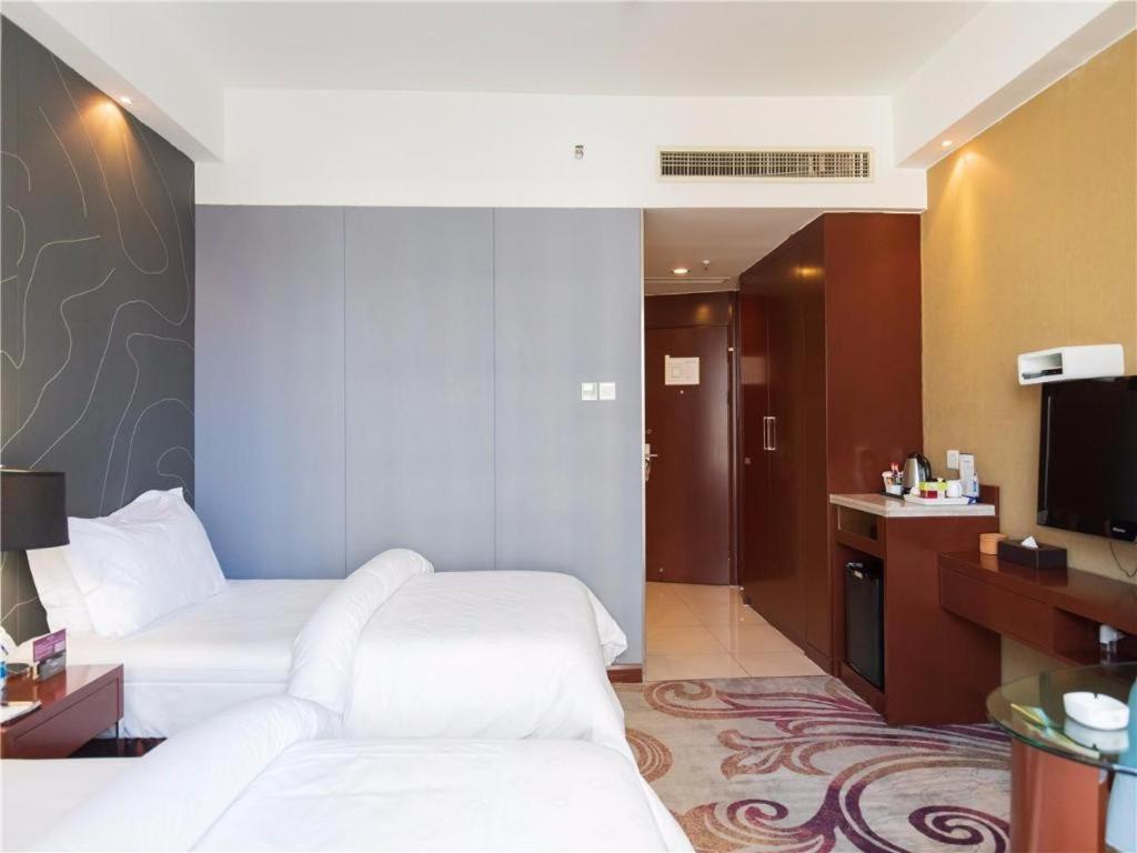 a hotel room with two beds and a television at Metropolo Hotel Financial Street Wanda Plaza in Fuzhou