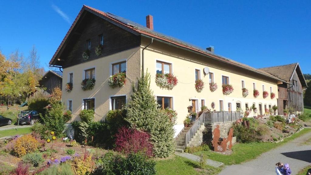 ein großes weißes Haus mit Blumenkästen an den Fenstern in der Unterkunft Huisnhof in Arrach