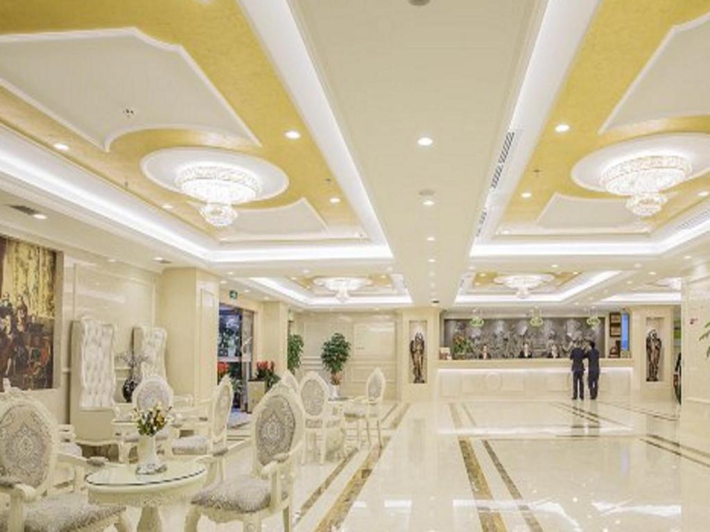 eine große Lobby mit weißen Stühlen und einer Person, die darin geht in der Unterkunft Vienna Hotel Guiyang Jiaxiulou Jichang Road in Guiyang