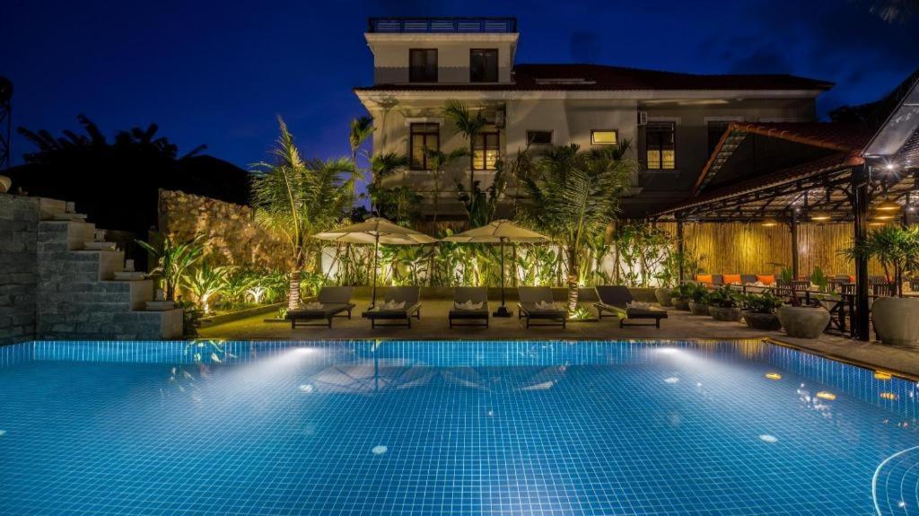 a hotel with a swimming pool at night at The Cyclo Siem Reap Hotel in Siem Reap