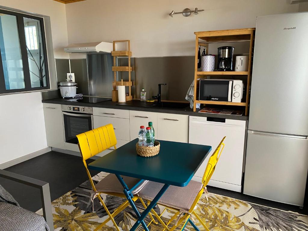 a kitchen with a blue table and yellow chairs at Location saisonnière A portée de vue in La Possession