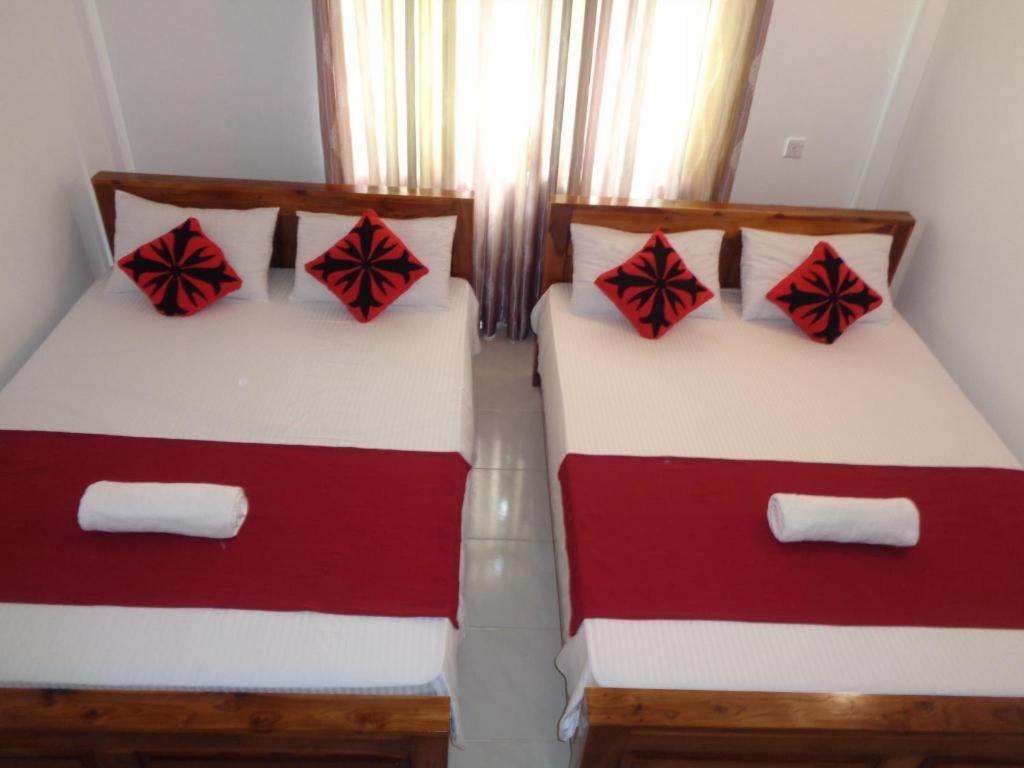 two beds in a room with red and white sheets at Riverdale holiday Inn in Kanduruwela