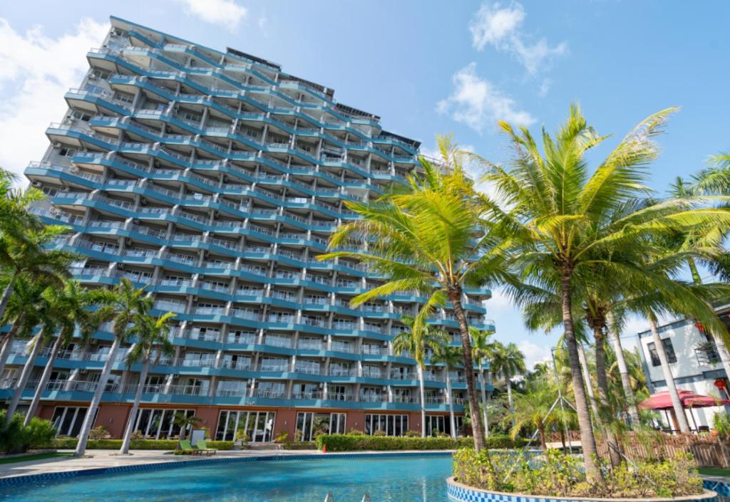 a large building with palm trees in front of a pool at Kingreal seaview resort sanya in Sanya