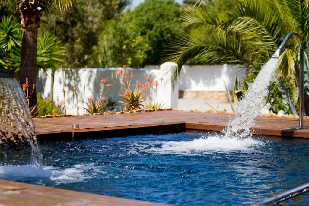 a water fountain in a pool with a wooden deck at Hotel Boutique Ses Pitreras in San Antonio Bay