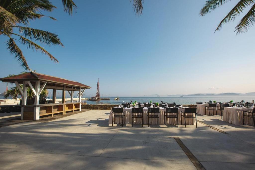 ein Pavillon mit Tischen und Stühlen am Strand in der Unterkunft Shenzhen Dameishawan Youtinghui Hotel in Shenzhen