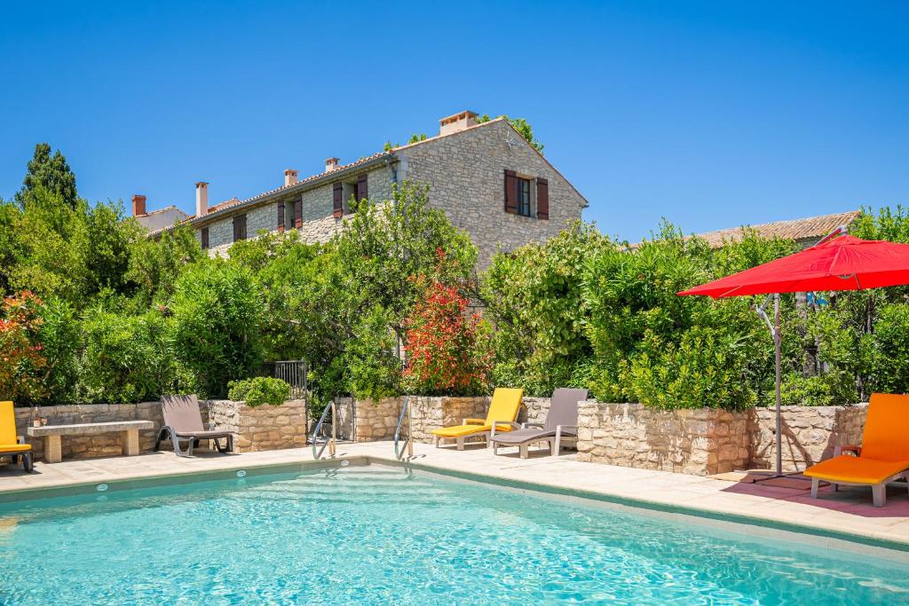 - une piscine avec des chaises et un parasol rouge dans l'établissement La Maison de Sophie, à Châteauneuf-de-Gadagne