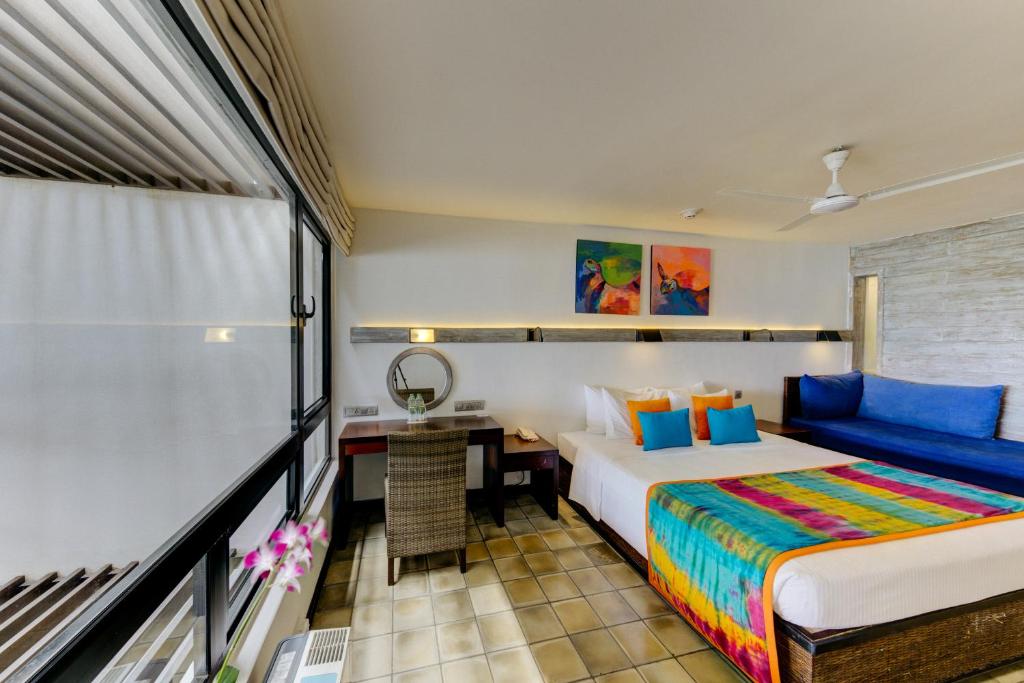 a bedroom with a bed and a desk in a room at Hikka Tranz by Cinnamon in Hikkaduwa