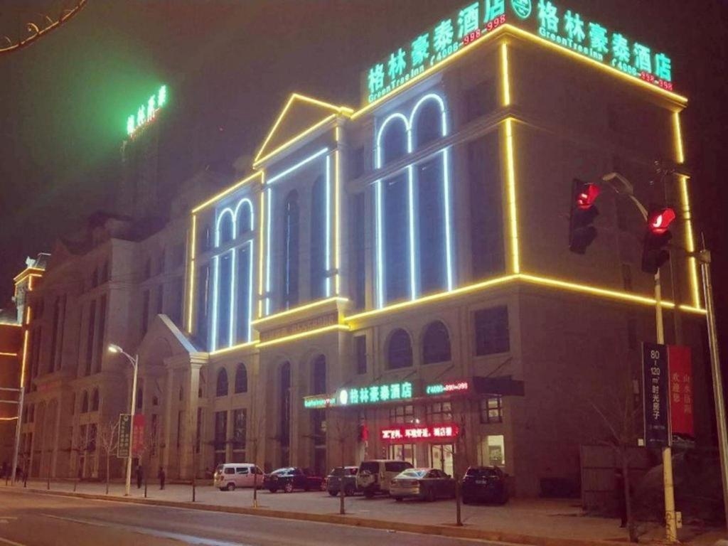 un edificio iluminado en una calle de la ciudad por la noche en GreenTree Inn Luoyang Train Station Zhuangyuanhong Road Hotel, en Luoyang