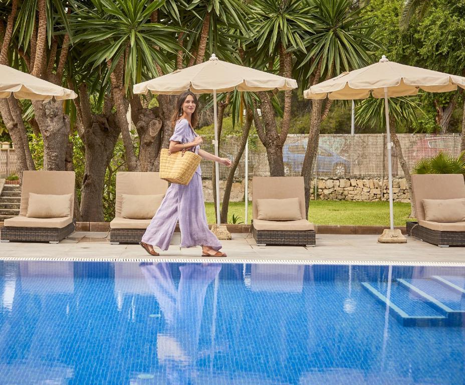 a woman walking next to a swimming pool at NURA Condor in Playa de Palma