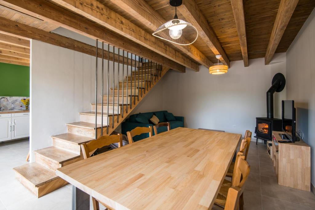 a dining room with a wooden table and stairs at Gîte le Belvezou - Charmante maison de campagne in Vézins-de-Lévézou