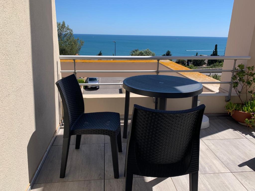 une table et des chaises sur un balcon avec vue sur l'océan dans l'établissement Sète - vue mer imprenable, piscine, calme, à Sète