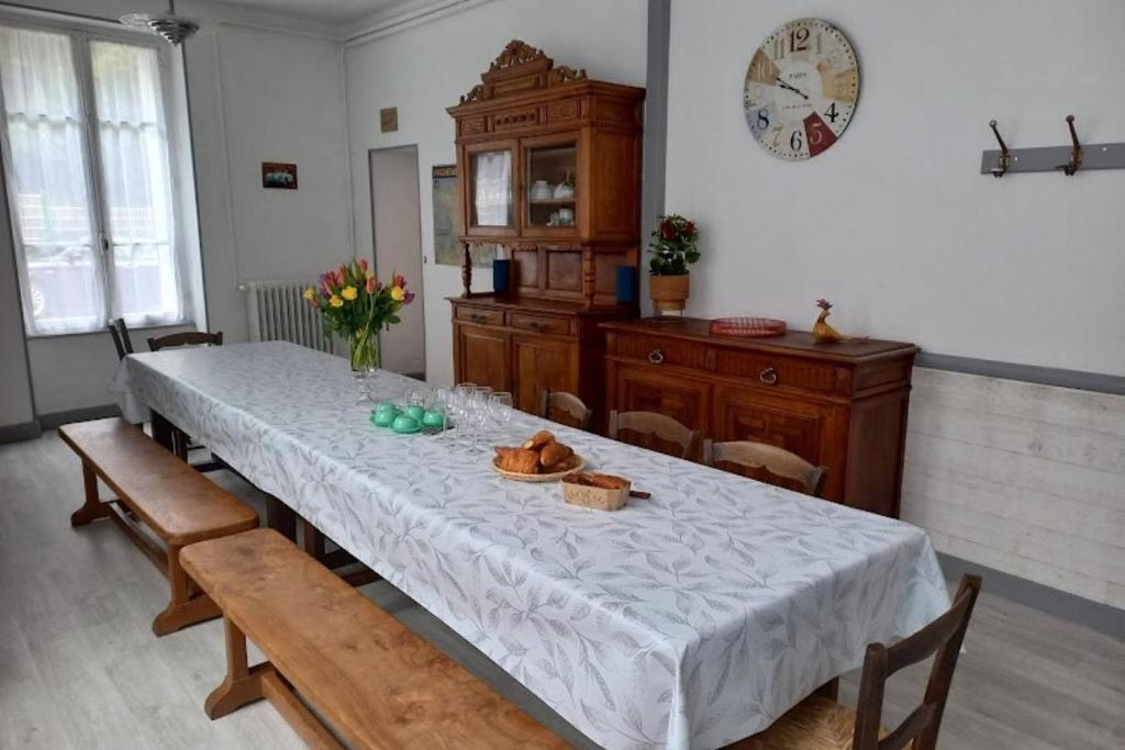 une salle à manger avec une table, des chaises et une horloge dans l'établissement Villa le bois Joli, à La Bourboule