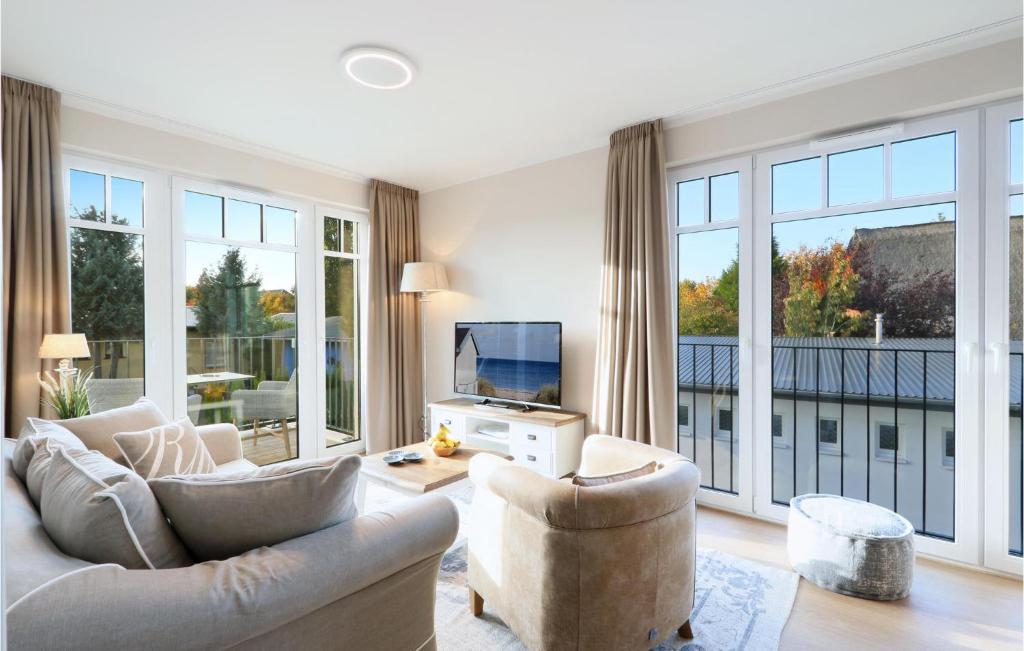 a living room with two chairs and a tv and large windows at Baltischer Hof Apartment 31 in Boltenhagen