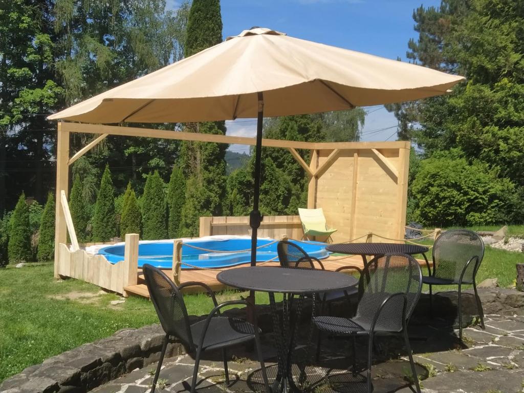 a table and chairs under an umbrella next to a pool at Willa na Bani - apartamenty i pokoje in Rabka