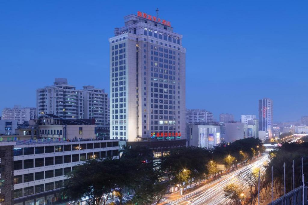 a tall white building in a city at night at Xinyuan Hot Spring Hotel in Haikou