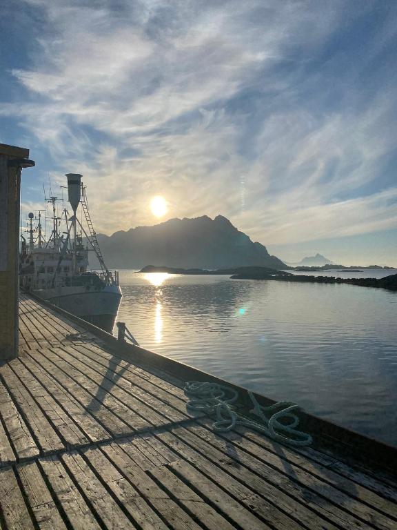 a boat is docked next to a dock with the sunset at Lofoten Sea Lodge in Sennesvik