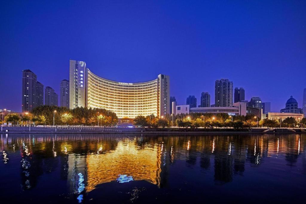 a large building with a reflection in the water at night at Banyan Tree Tianjin Riverside in Tianjin