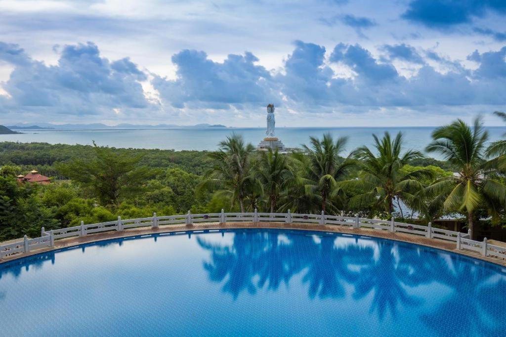 a pool with a view of the ocean and a lighthouse at Nanshan Leisure Villas in Shangsimacun