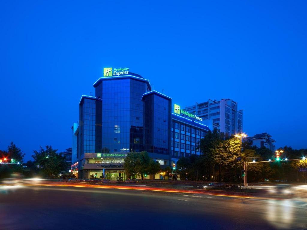 a city street with a tall building at night at Holiday Inn Express Yangzhou City Center By IHG in Yangzhou