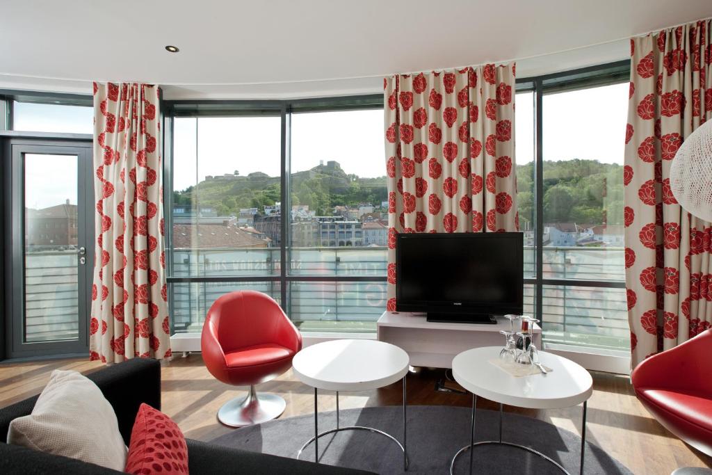 a living room with red chairs and a television at Thon Hotel Halden in Halden