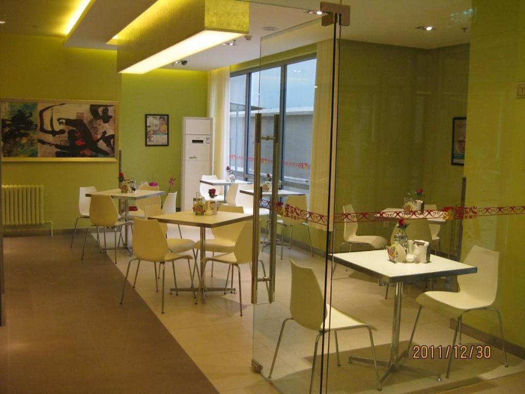 a restaurant with tables and chairs in a room with green walls at Jinjiang Inn Beijing Huairou Qingchun Road Wanda Plaza in Huairou