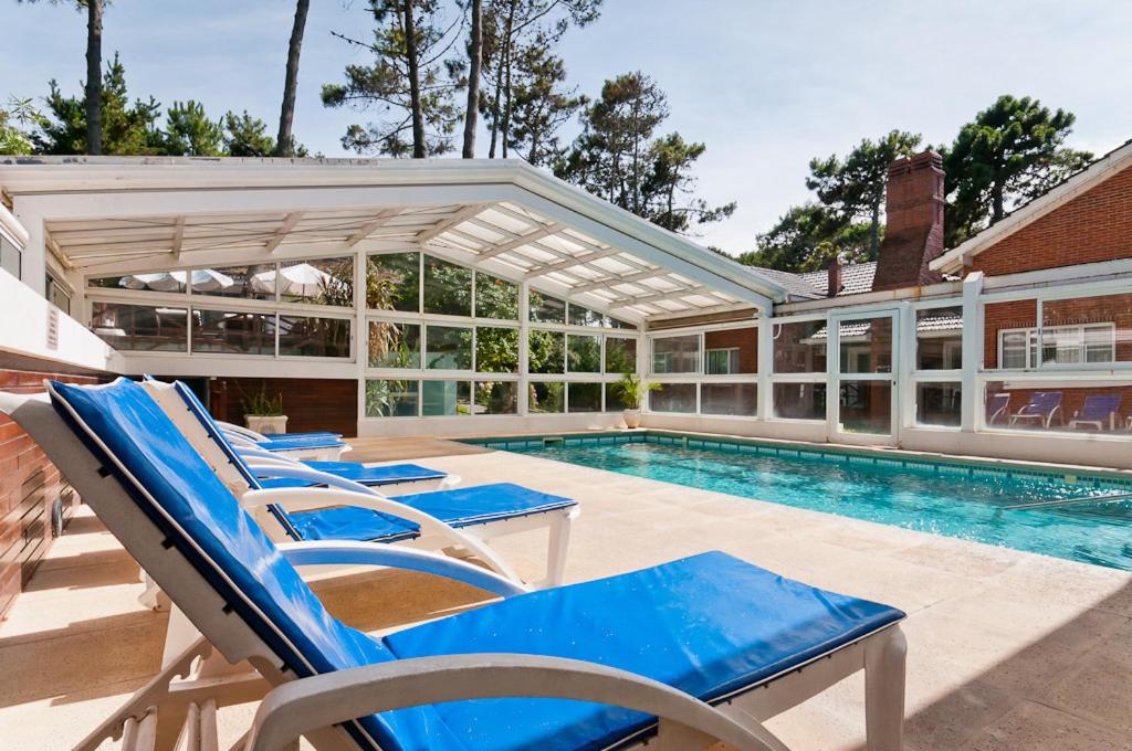 a swimming pool with blue lounge chairs and a house at Las Cuatro Estaciones in Carilo