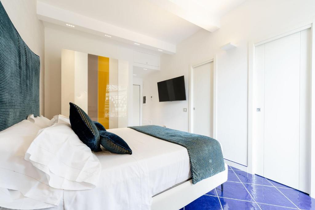 a bedroom with a white bed with blue pillows at La Suite Del Cavaliere in Amalfi