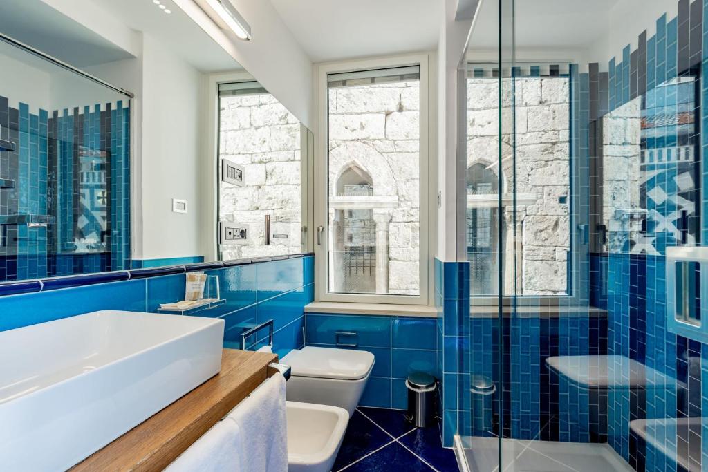 a bathroom with blue tiles and a tub and a sink at La Suite Del Cavaliere in Amalfi