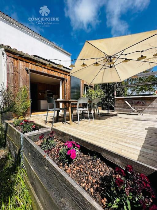 une terrasse en bois avec une table et un parasol dans l'établissement L'Authentique - Charmante maison, à La Tremblade