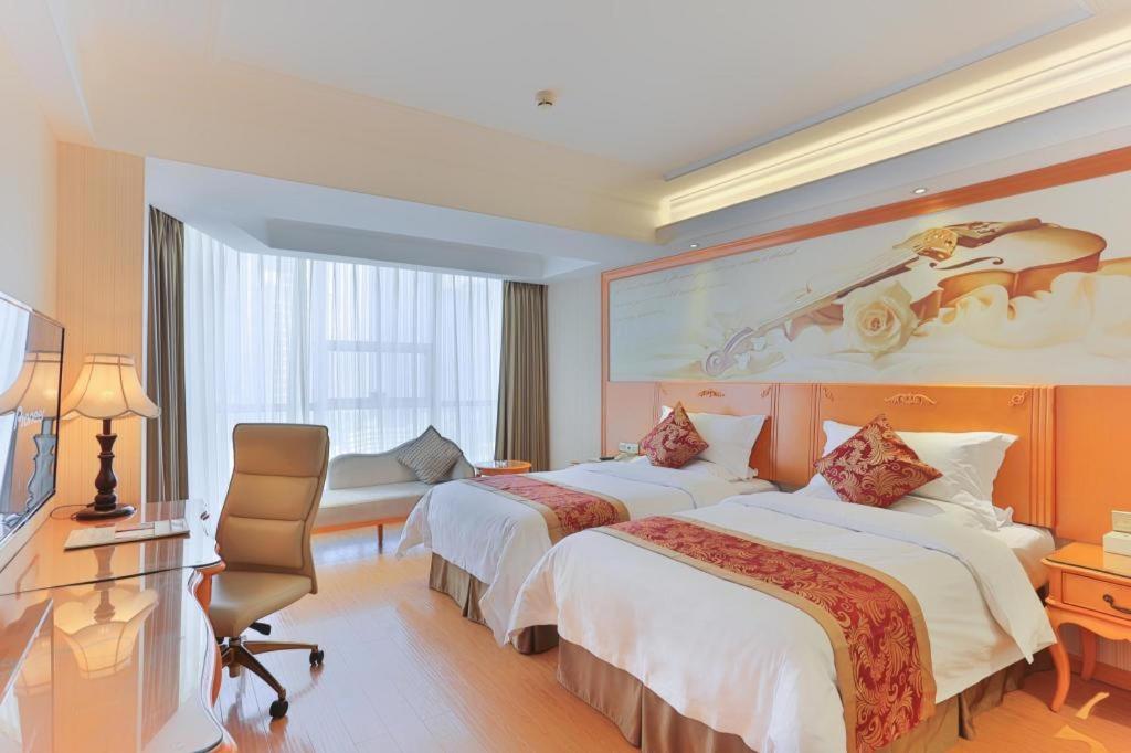 a hotel room with two beds and a desk at Vienna Hotel Tianjin Guizhou Road Branch in Tianjin