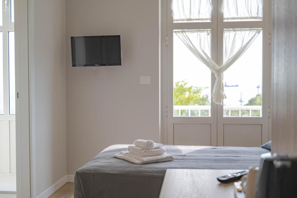 a bedroom with a bed with a tv and a window at Hotel Tritone in Trieste