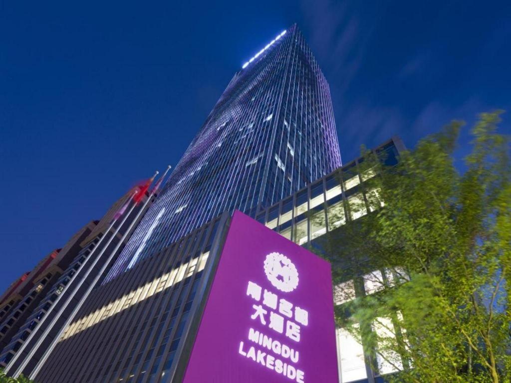 un edificio alto con un cartello davanti di Ming Du Lakeside Hotel Nanning a Nanning