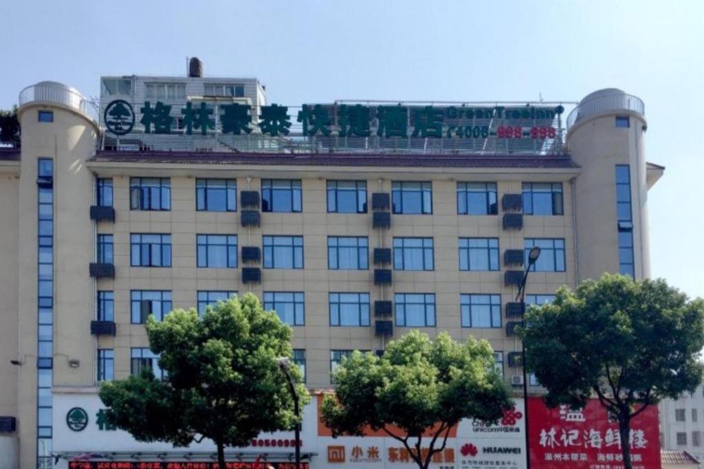 ein großes Gebäude mit Bäumen davor in der Unterkunft GreenTree Inn Jiangsu Wuxi Xishan DongTing Erquan East Road XinGuang Newly Estate Express Hotel in Wuxi