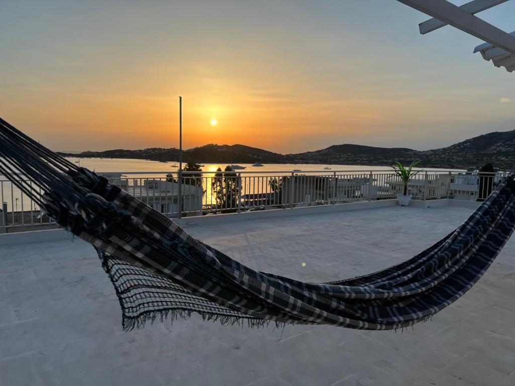 a hammock on a beach with the sunset in the background at Athens Palaia Fokaia Entire Flat 2 bedrooms with panoramic sea views and a massive veranda , only steps away from the beach and amenities in Palaiá Fókaia