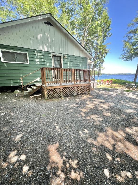 a green house with a deck next to the water at PLACYD PINES LIMIT 8 cottage in North Sebago