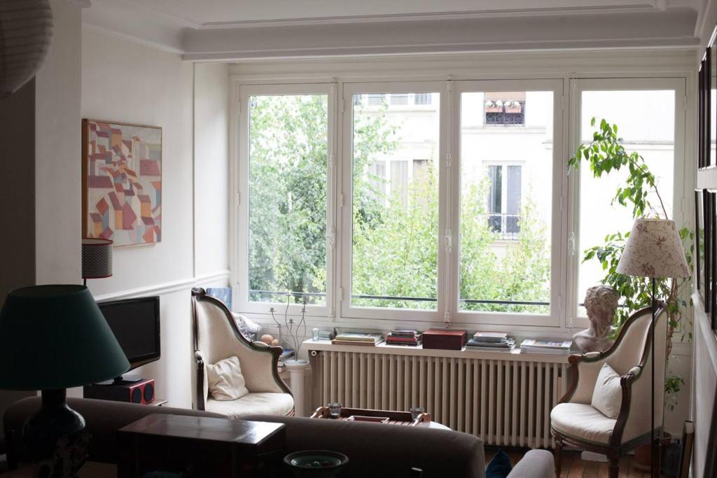 - un salon avec deux chaises, un canapé et deux fenêtres dans l'établissement So Cute 55m2 And Quiet With A Courtyard Garden, à Paris
