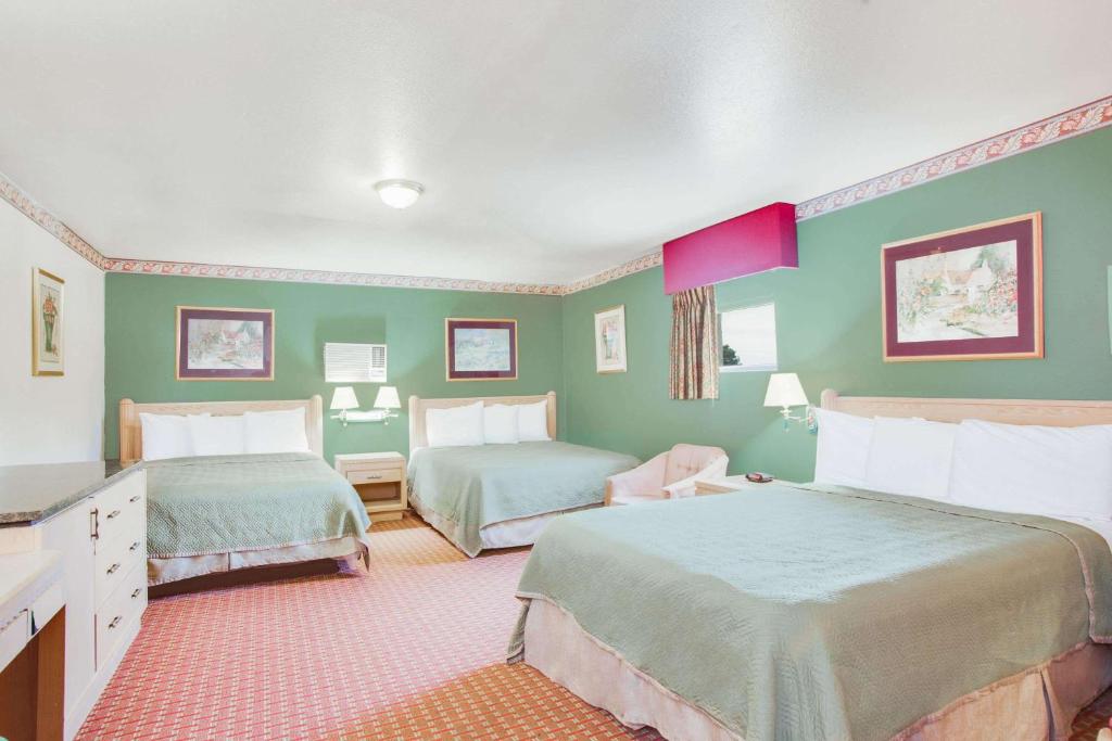 two beds in a room with green walls at Rodeway Inn Memphis in Memphis