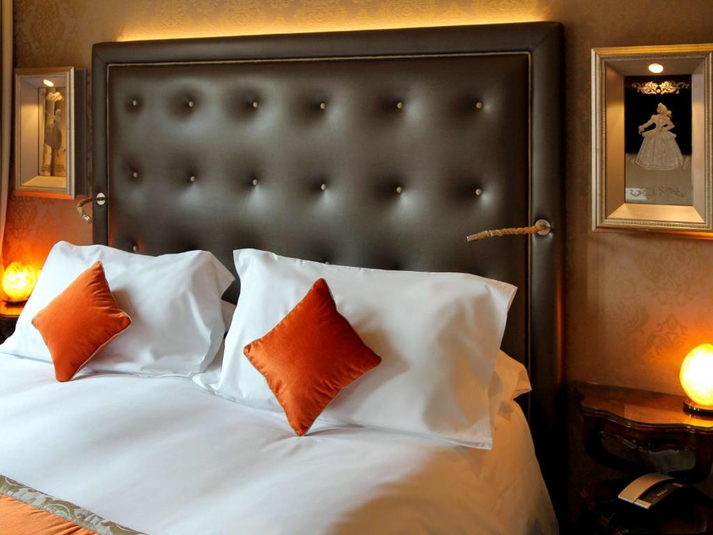 a bedroom with a bed with orange and white pillows at Papadopoli Hotel Venezia - MGallery Collection in Venice
