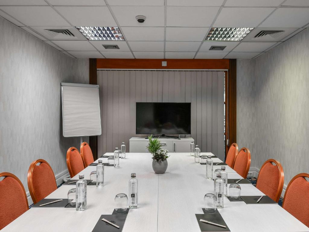 a conference room with a table and chairs and a screen at Pullman Bucharest World Trade Center in Bucharest