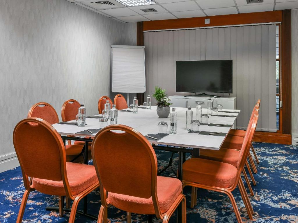 a conference room with a table and chairs and a screen at Pullman Bucharest World Trade Center in Bucharest