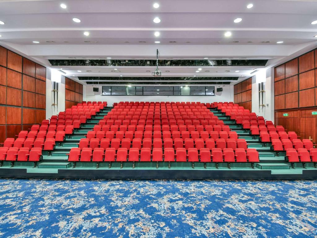 an empty auditorium with red seats in a building at Pullman Bucharest World Trade Center in Bucharest