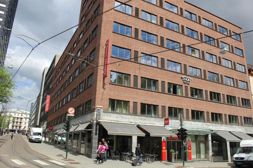 a tall brick building on a city street with people walking past it at Thon Hotel Europa in Oslo