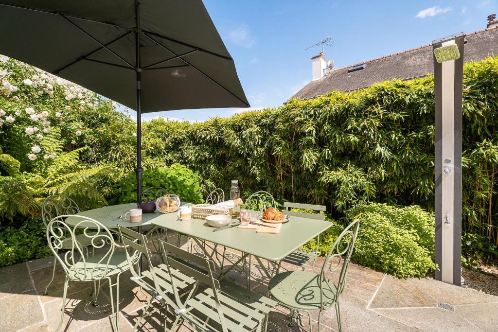 a table and chairs with an umbrella on a patio at Grande maison-Marché-10pers-jacuzzi-parking in Dinard