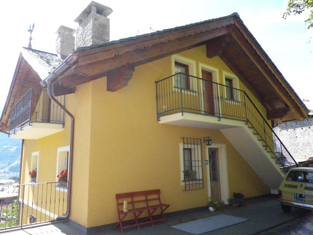 ボルミオにあるAppartamento Centro Storicoの黄色の家 バルコニー2つ ベンチ付