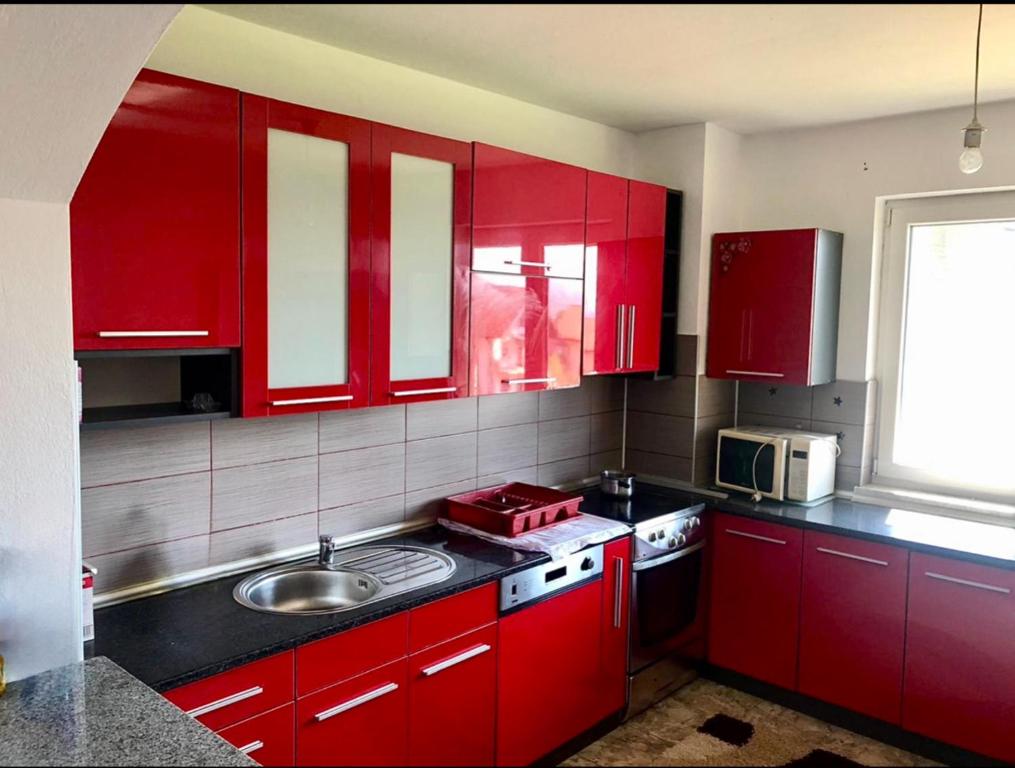 eine Küche mit roten Schränken und einer Spüle in der Unterkunft Apartment Panonija in Tuzla