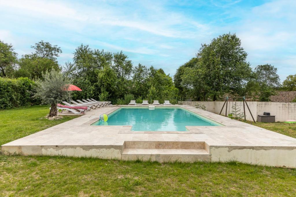 - une piscine dans une cour avec des chaises et un parasol dans l'établissement Le Magicogite - Harry Potter, à Larocal