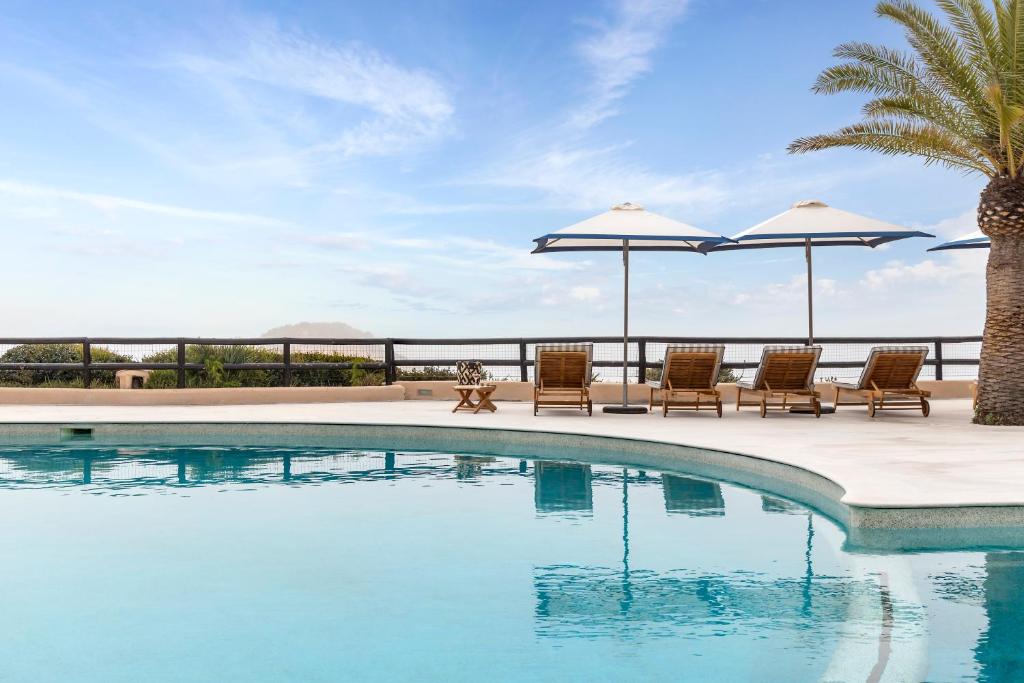 - une piscine avec des chaises longues et des parasols dans l'établissement Vilalara Grand Hotel Algarve, à Armação de Pêra